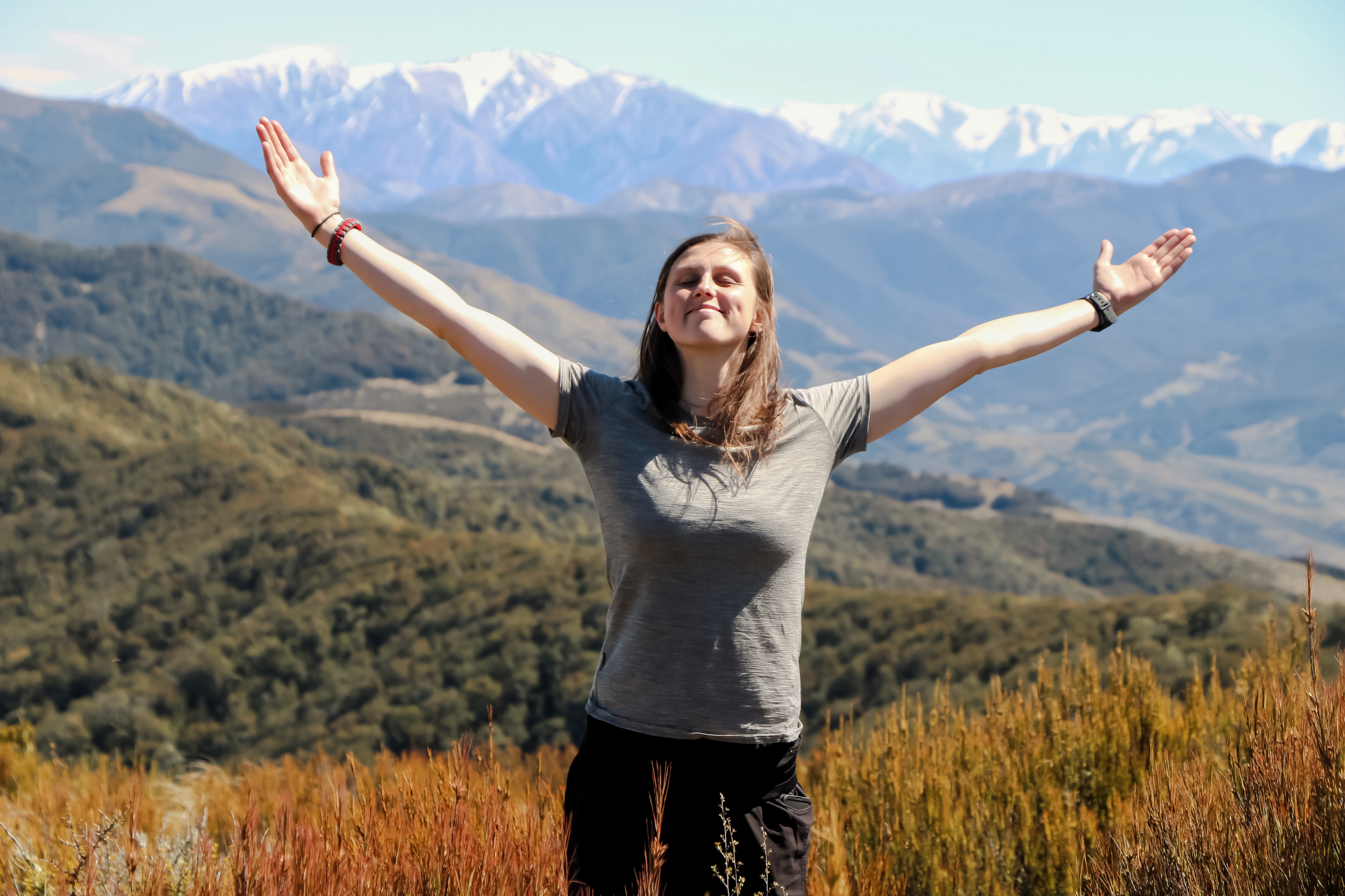 Girl in front of mountains with arms wide open